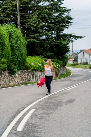 Joyful woman walking on marked road looking away