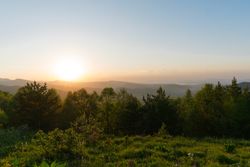 Sunset over forested hills with sky.