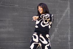 Smiling dancer performing in the street next to grey wall