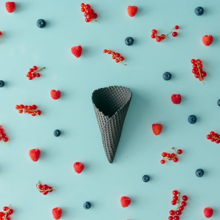 Dark waffle cone on blue background with berries