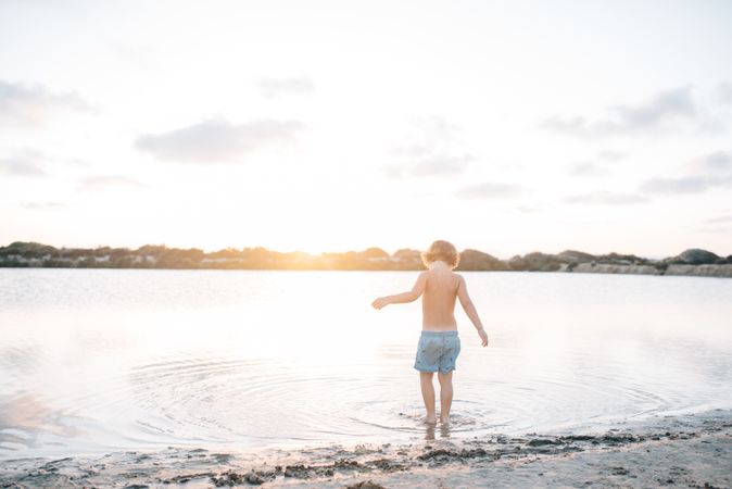 Boy walking in water of lake