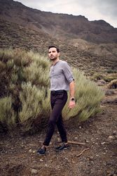 Stylish male strolling on mountain slope near savanna grass