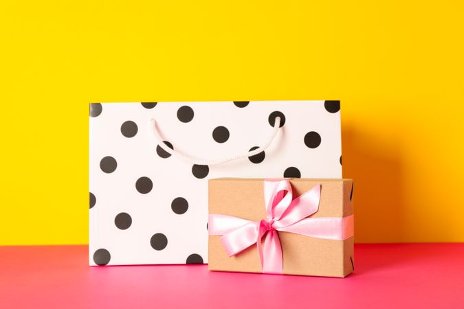 Paper bag with present on multicolor background, space for text