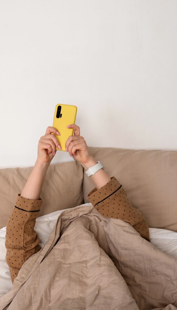 Hand with smartphone under covers