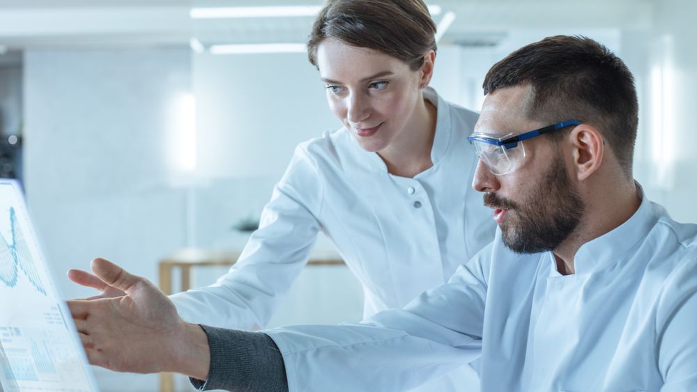 In the Futuristic Laboratory Male and Female Scientists Talk While Working on the Transparent Display Computer.