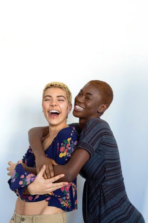Affectionate female couple embracing and laughing in studio