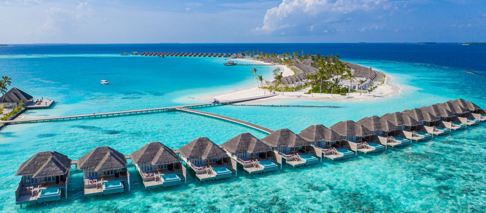 Villas lined up in the water of a tropical beach, wide
