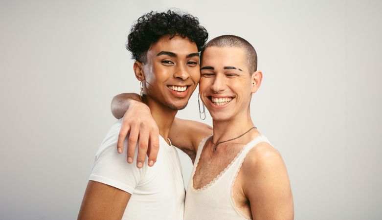Cheerful male couple smiling on light background