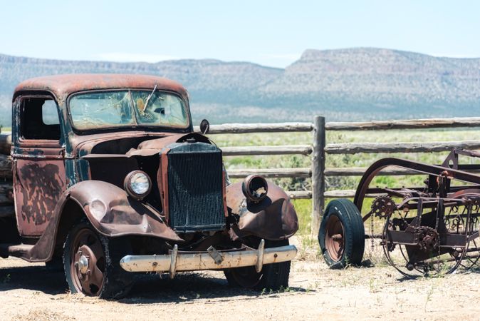 Old rusty car by wooden fence in rural area