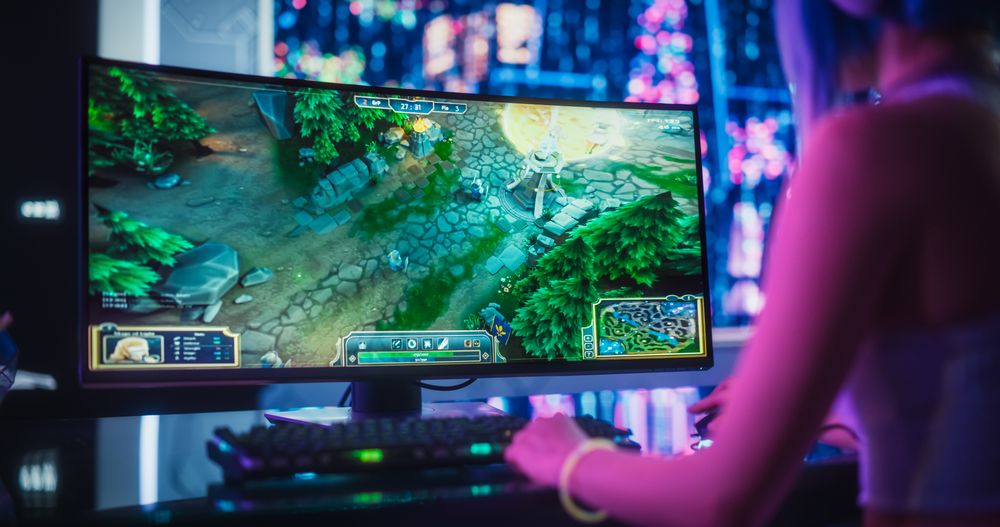 Stylish Female Gamer Playing Fantasy Strategy Video Game with Modern Graphics on Her Computer.