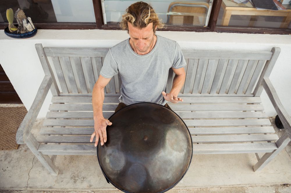 Blond man sitting on bench with big hand drum