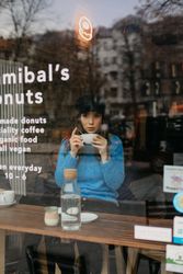 stylish woman drinking coffee into a coffee shop looking away