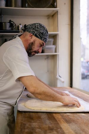 Adult baker rolling out dough