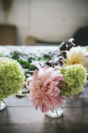 Table with set of flowers in glasses in room