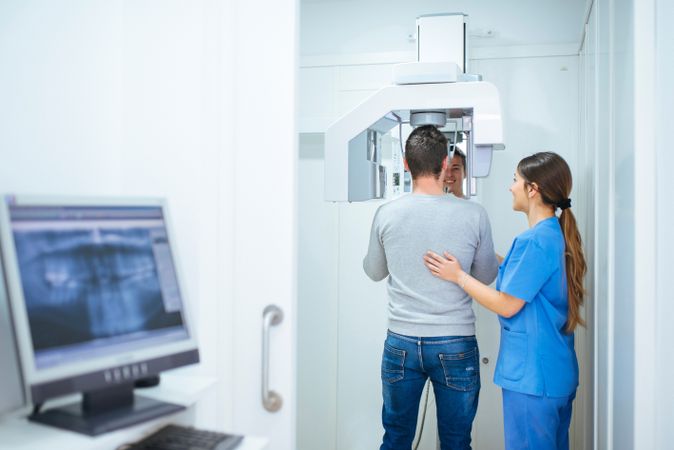 Dental assistant helping client to do x-ray