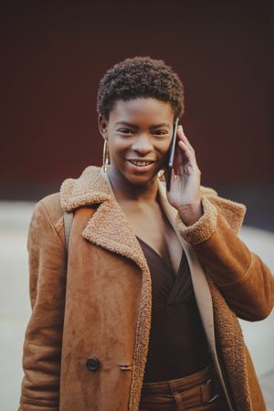 Stylish Black woman talking on smartphone on street