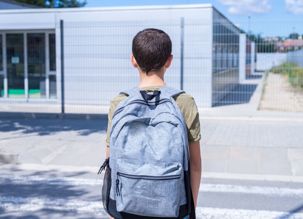Teenage school boy with a backpack walking to school