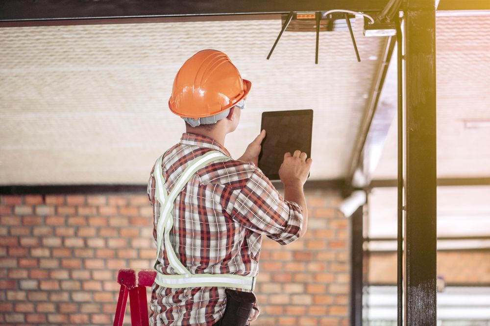 Back view of an engineer in bump cap using tablet computer