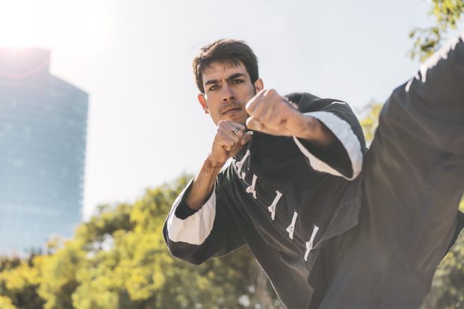martial arts fighter practicing kicks outdoors while looking at camera. Copy space