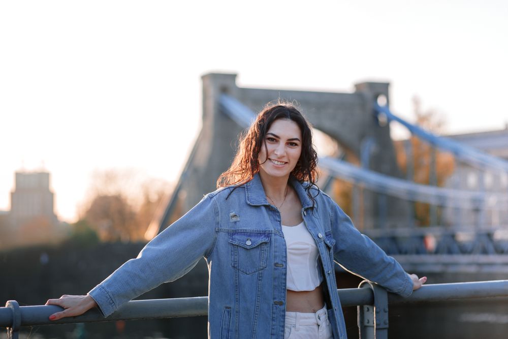 Woman standing by bridge along the waterfront at sunset