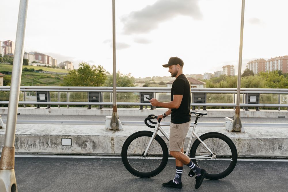 Man walking with bike and using smartphone