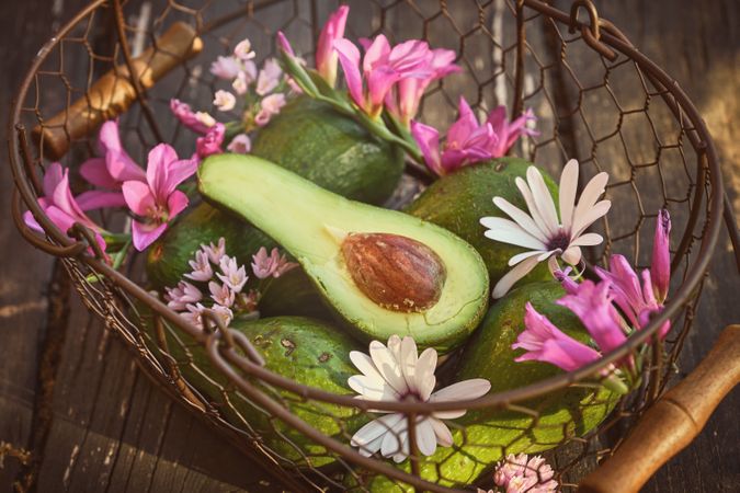 Fresh green avocado with flowers in basket