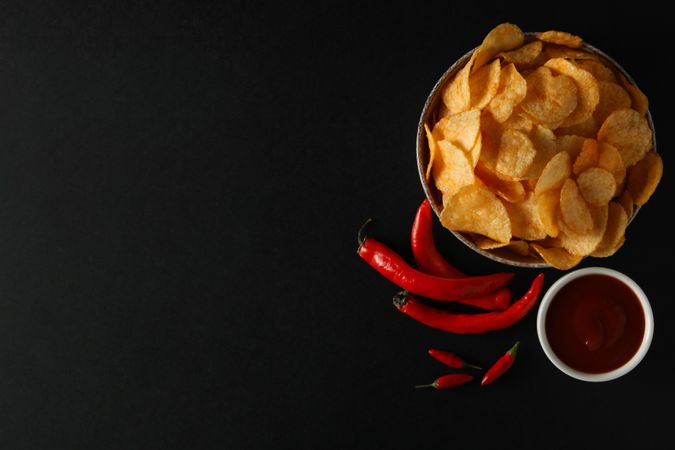 Potato chips in a black bowl on a dark background
