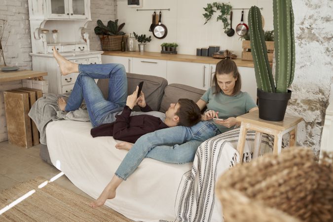 Chilling couple spending time together on sofa browsing smartphone