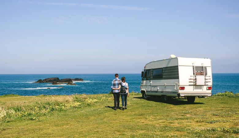 Couple taking a walk near the coast with a camper