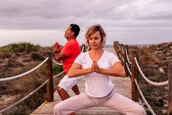 Adult couple meditating on wooden path