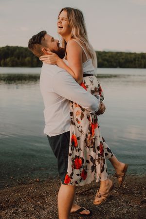 Loving man carrying happy woman on hands on shore