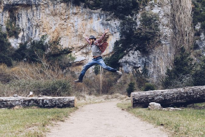Excited man jumping on trunk in nature