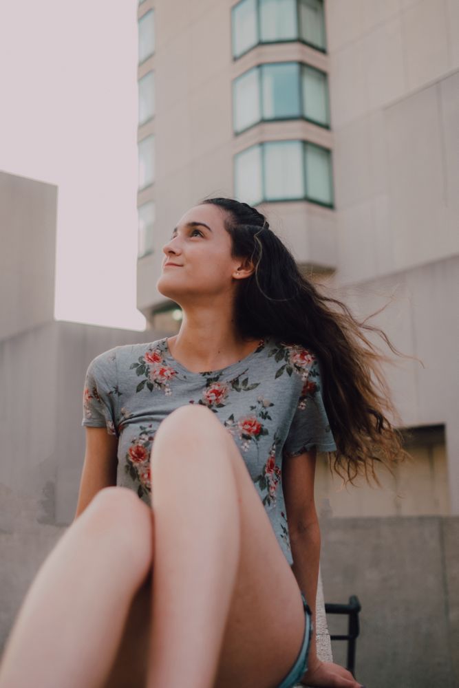 Smiling modern woman sitting on parapet