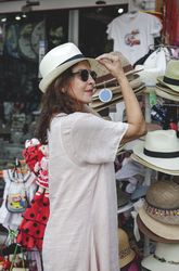 Woman choosing summer hat on street market