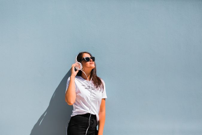 Cheerful casual woman in sunglasses standing on city street