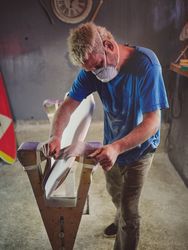 Attentive male surfboard shaper polishing template edges with sa