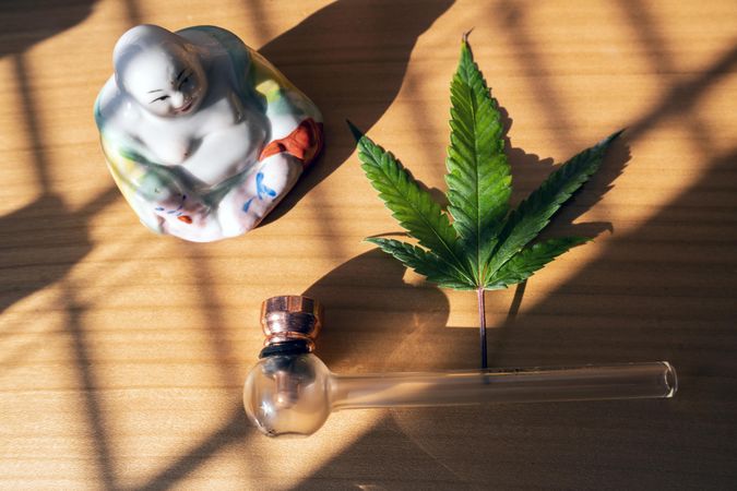 Buddha statue with marijuana leaf and pipe