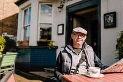 Man at an outdoor cafe with cup of coffee 0JeJvb