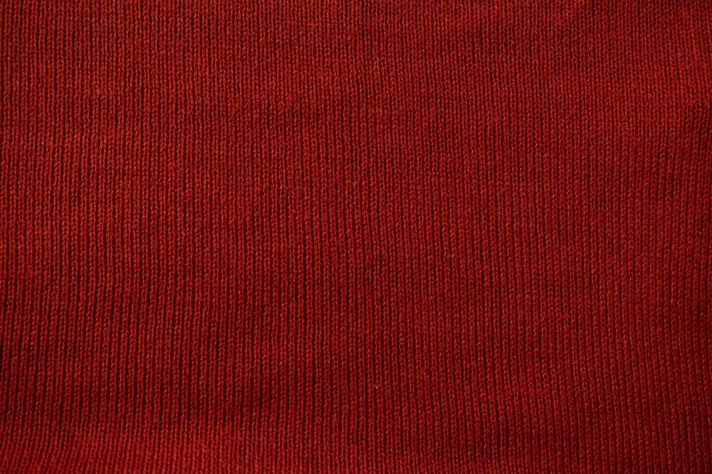 Detailed red knitted fabric background texture.
