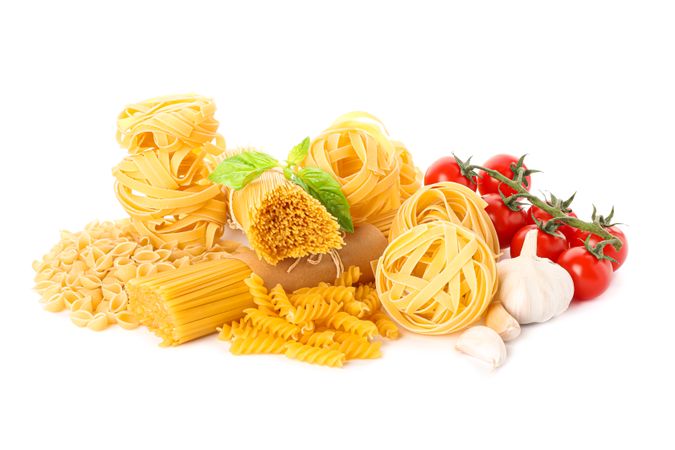 Pasta and vegetables isolated on light background. Uncooked whole wheat pasta