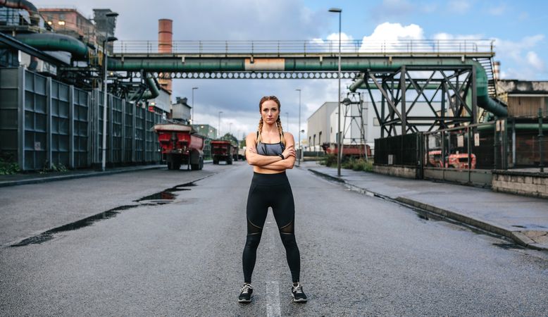 Sportswoman looking camera posing in front of a factory