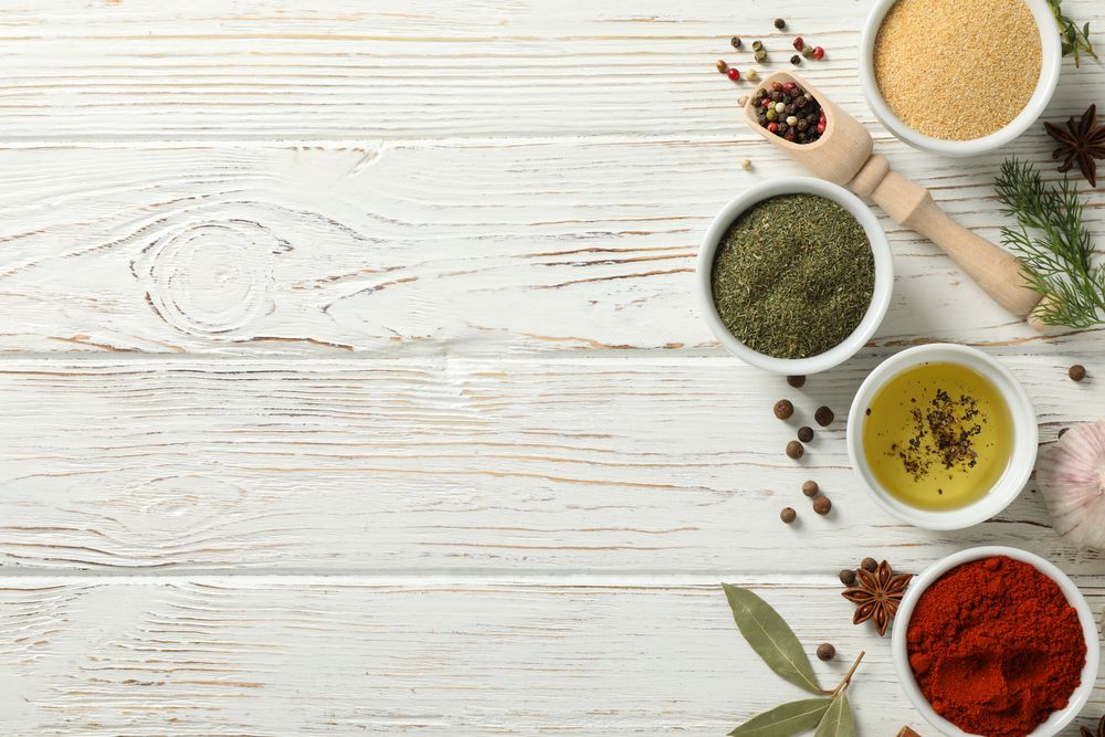 Top view of wooden scoop full of peppercorn with bowls of spice, copy space