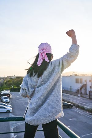 Woman in pink scarf raising fist against breast cancer