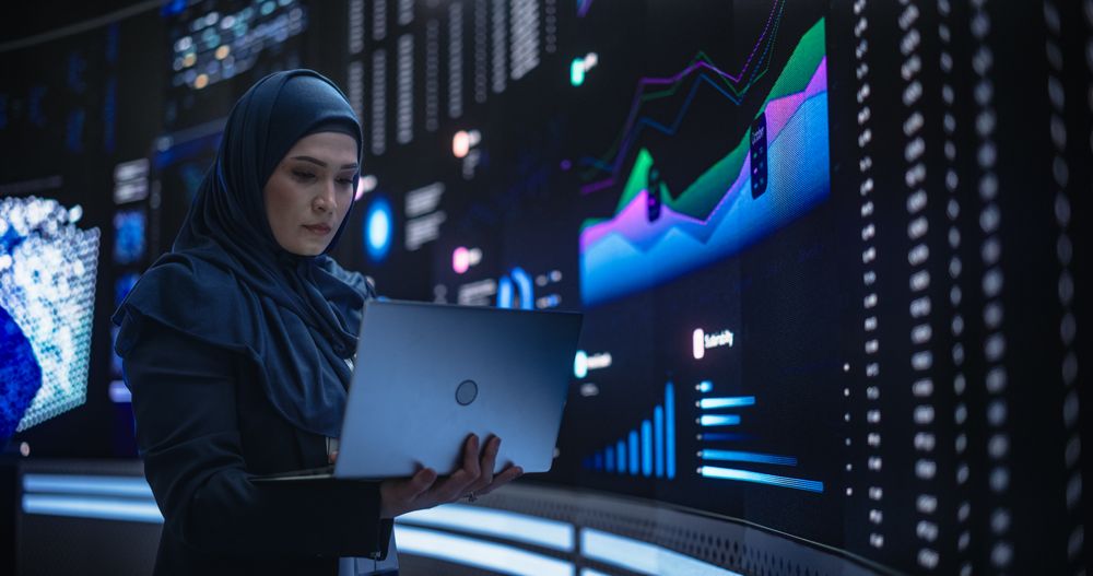 Muslim Female Data Center IT Engineer Standing in a Room with an AI Neural Network Settings on a Digital Screen.