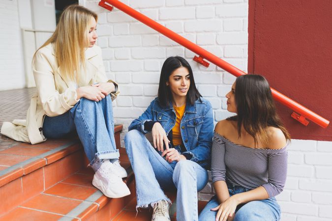 Three women talking with each other on outdoor brick steps