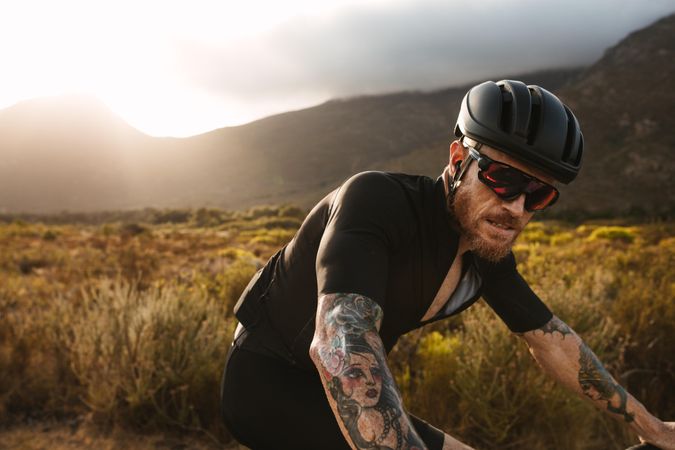 Fit man with tattoos on bicycle ride through the mountains