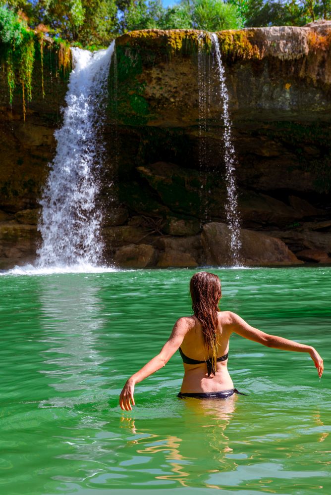 Anonymous female standing near amazing waterfall