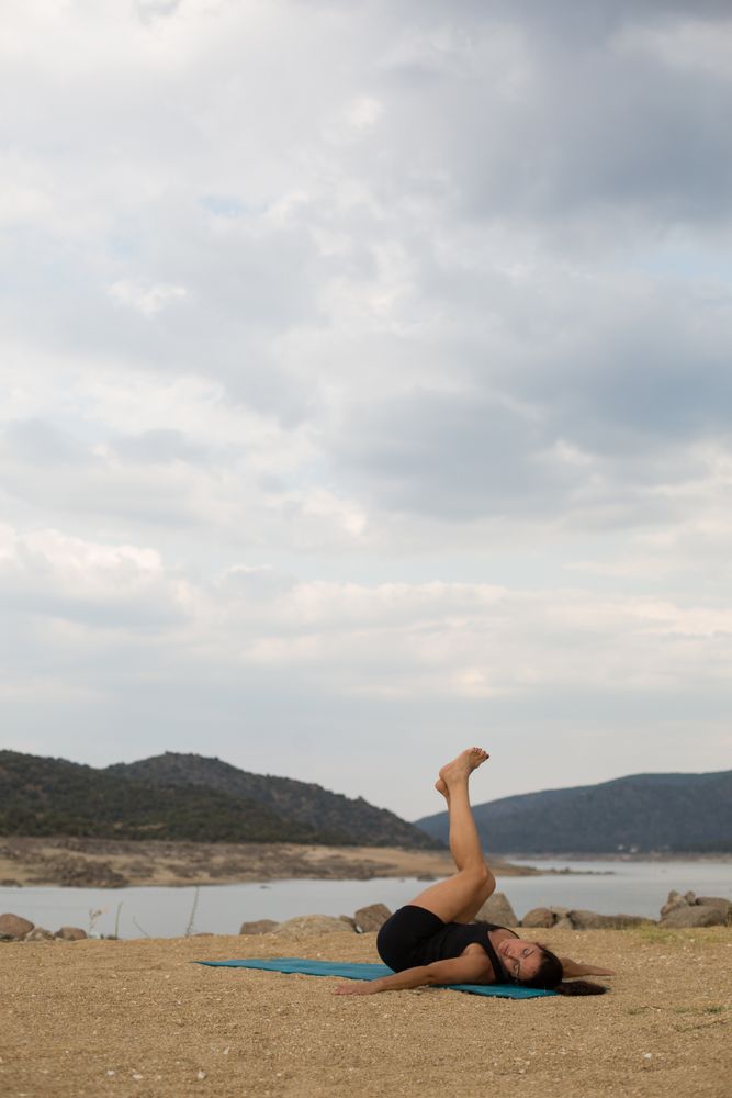 Woman practicing yoga outdoors near water