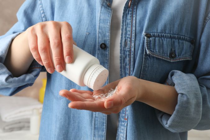 Mom applying talc powder from plastic tube. Baby hygiene