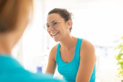 A woman patient talks cheerful to her physiotherapist after receiving a manual therapy session